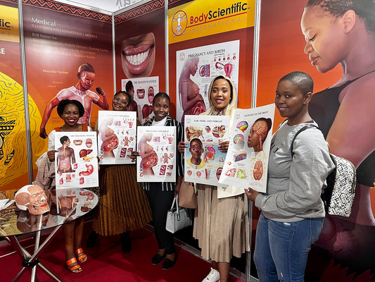 visitors at the Body Scientific stand, at Africa Health 2022, holding up anatomical charts depicting medical illustrations of black people.